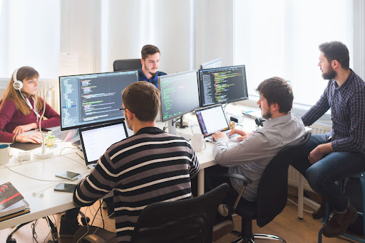 Équipe de développeurs au travail devant plusieurs écrans de code