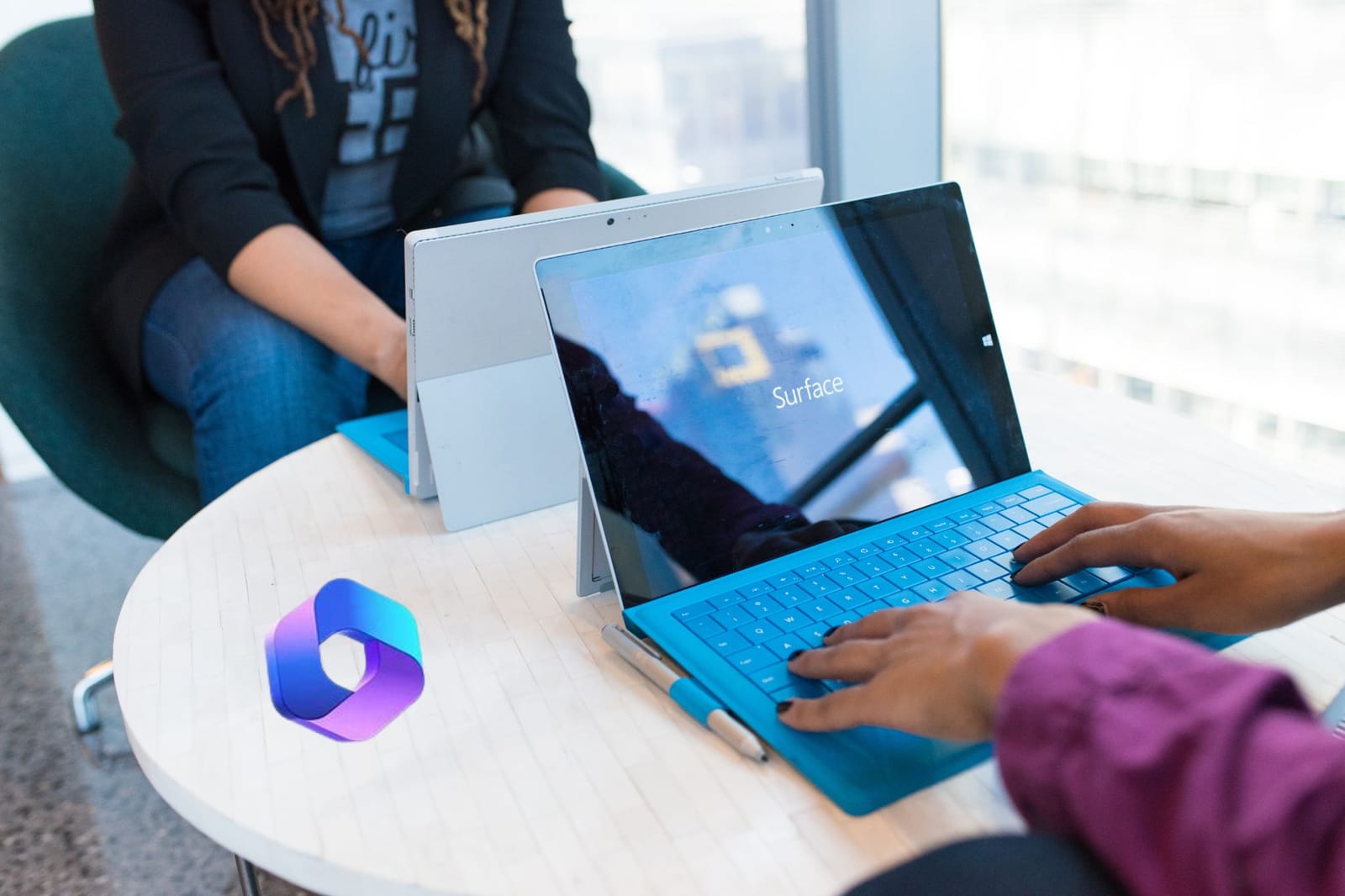 Personne qui travaille sur une tablette Surface avec clavier, logo Microsoft 365 posé sur la table